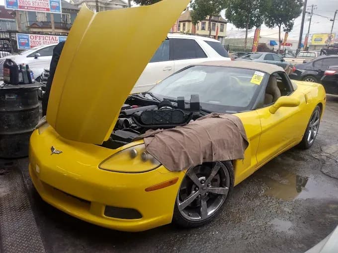 A yellow Corvette in for service with the hood up