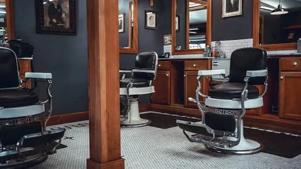 Inside the shop: vintage barber chairs, wood mirrors, and a white tile floor