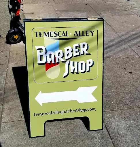 The shop's green sidewalk sign with an arrow pointing into the alley